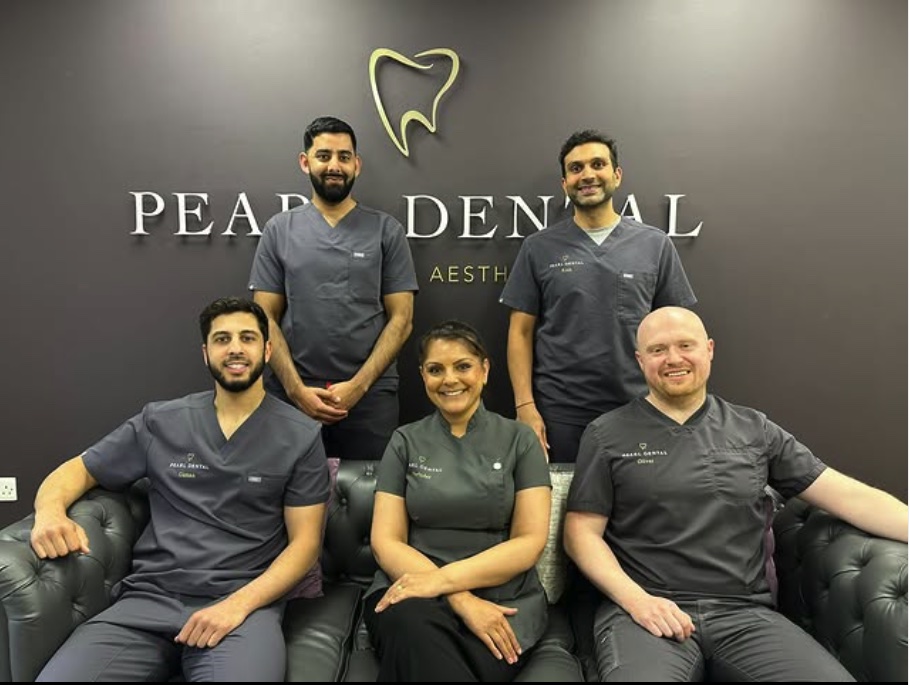 Five of the Pearl Dental clinical team beneath the gold tooth sign